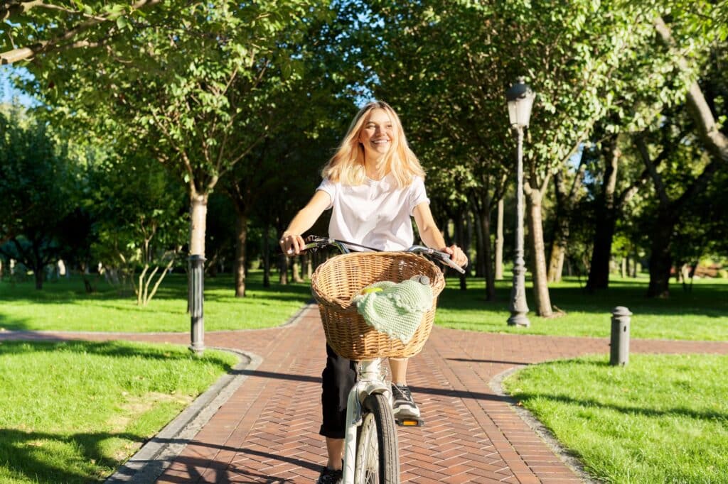 Les avantages du vélo électrique pour les femmes 8 Young beautiful woman on vintage bike with basket rides on nature